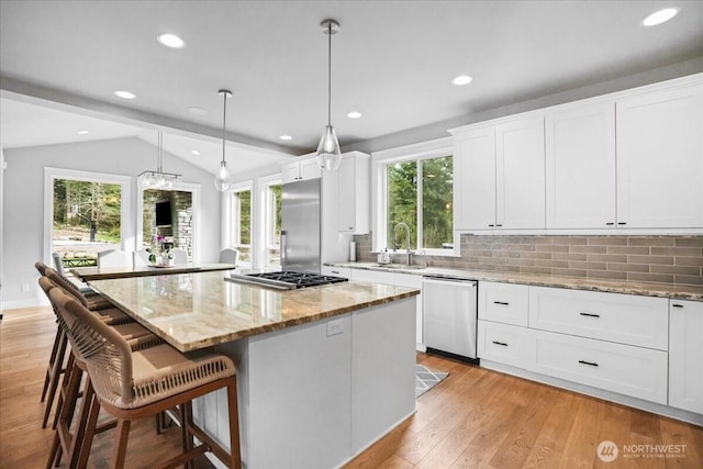 kitchen with a center island, a sink, appliances with stainless steel finishes, and a healthy amount of sunlight