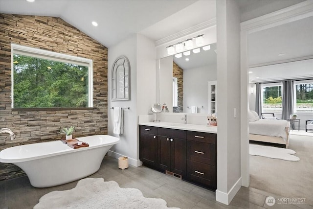 ensuite bathroom with vanity, vaulted ceiling, wood finished floors, a freestanding tub, and ensuite bath