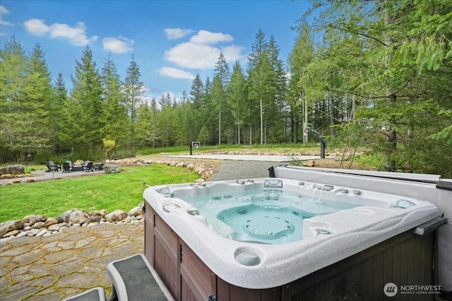 view of patio with a hot tub and a wooded view