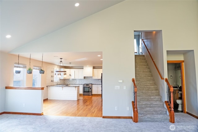 1509 Seahawk Dr, Ferndale, WA 98248 - kitchen featuring stainless steel gas stove, a sink, a peninsula, light carpet, and white cabinetry