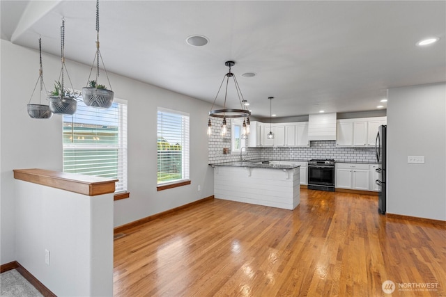 1509 Seahawk Dr, Ferndale, WA 98248 - kitchen with gas stove, freestanding refrigerator, light wood finished floors, custom range hood, and white cabinetry