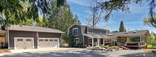 back of house featuring a deck, a garage, and gravel driveway