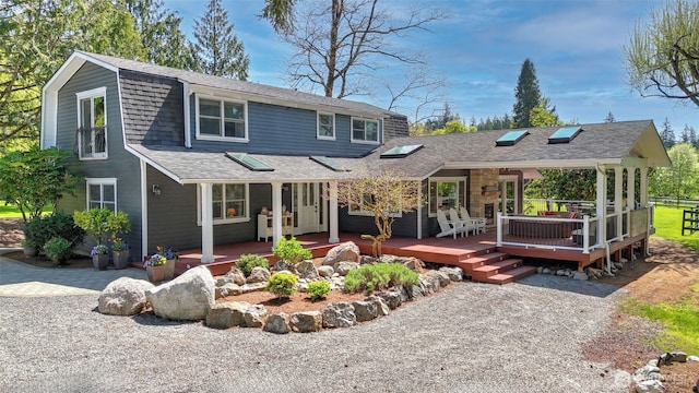 view of front facade with a gambrel roof, a wooden deck, and roof with shingles