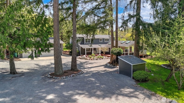 view of front facade featuring an outdoor structure, a porch, a storage shed, and curved driveway