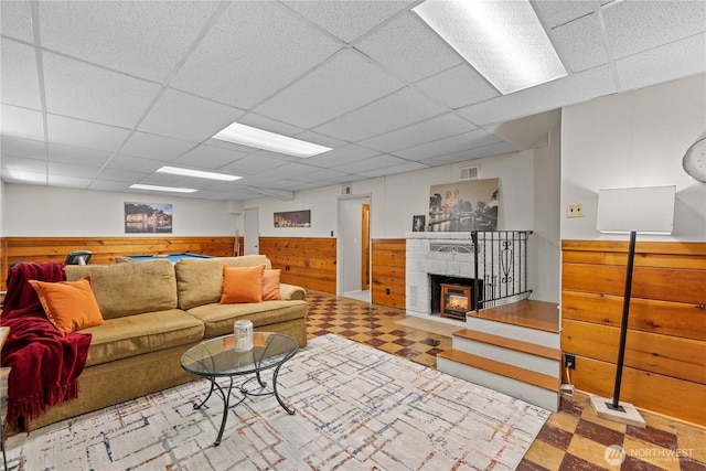1423 Springwater Ave, Wenatchee, WA 98801 - living room with tile patterned floors, a drop ceiling, wooden walls, wainscoting, and a fireplace with flush hearth