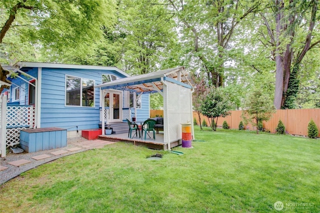 rear view of property featuring fence, a wooden deck, and a yard