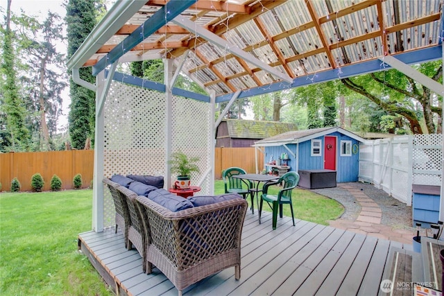 wooden deck with a storage shed, a fenced backyard, an outbuilding, outdoor dining area, and a lawn