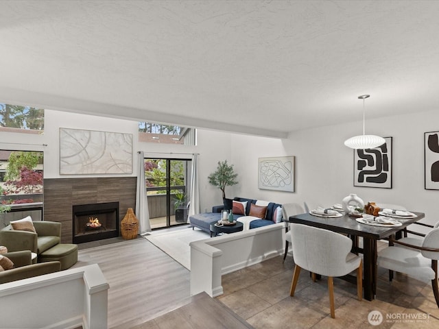 dining space featuring a tiled fireplace and light wood-style flooring
