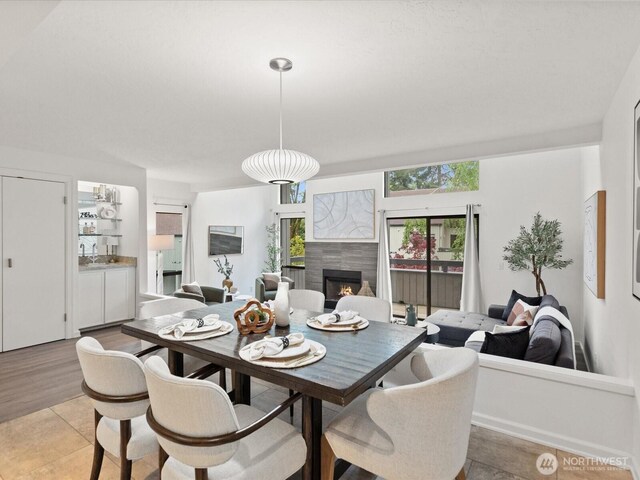 dining room featuring a tiled fireplace and light wood finished floors