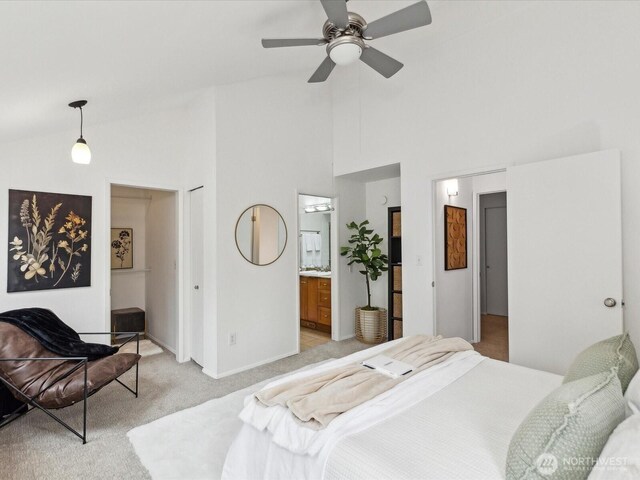 bedroom with a ceiling fan, high vaulted ceiling, baseboards, ensuite bathroom, and light carpet