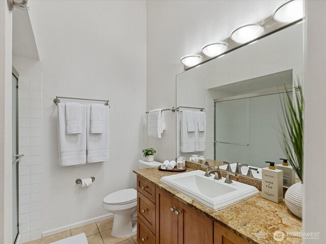 full bathroom featuring vanity, toilet, tile patterned floors, baseboards, and a stall shower