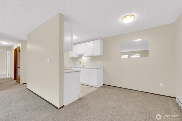 kitchen with light colored carpet, light countertops, white cabinetry, and baseboards