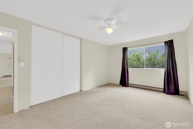 carpeted empty room featuring a baseboard radiator and ceiling fan