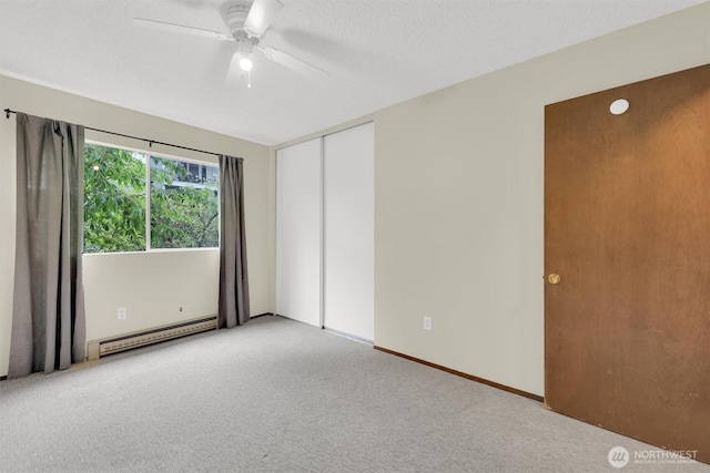 carpeted empty room featuring a ceiling fan and a baseboard heating unit