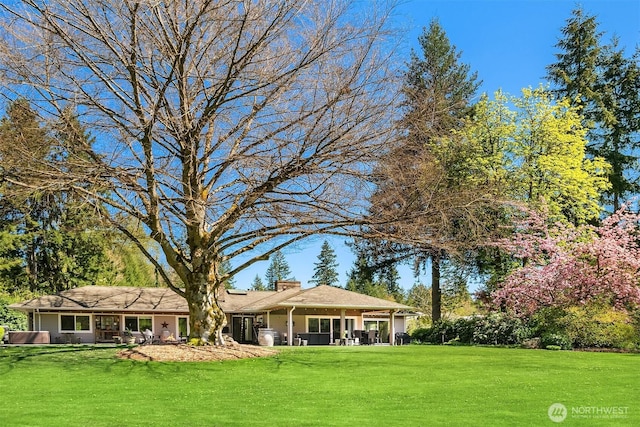 rear view of house featuring a lawn and a chimney