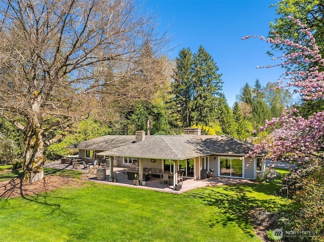 back of house featuring a patio, a yard, and a chimney