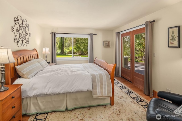 bedroom featuring access to exterior, multiple windows, and light wood finished floors