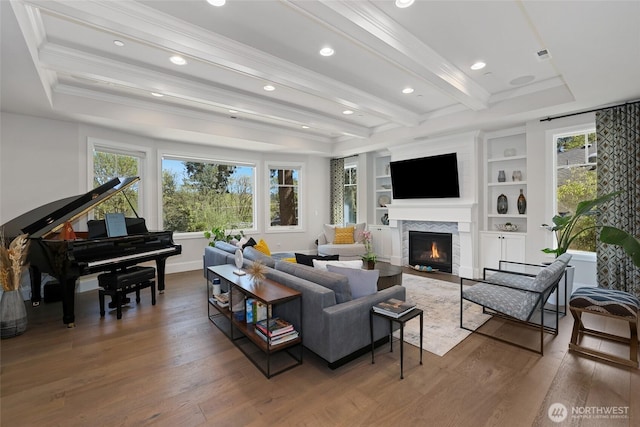 living area featuring a glass covered fireplace, wood finished floors, and a healthy amount of sunlight