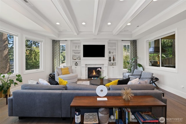 living room with wood finished floors, a warm lit fireplace, a wealth of natural light, and beamed ceiling