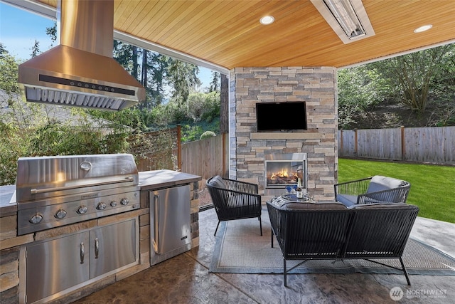 view of patio / terrace with area for grilling, an outdoor kitchen, a fenced backyard, and an outdoor living space with a fireplace
