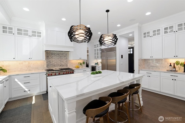 kitchen featuring dark wood-style flooring, a kitchen island, recessed lighting, tasteful backsplash, and stainless steel built in refrigerator