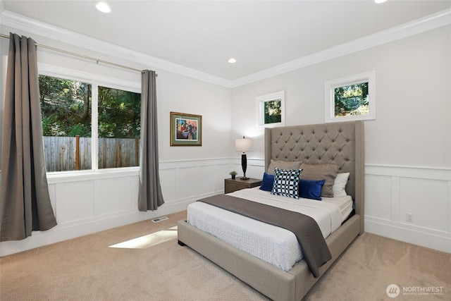 carpeted bedroom with crown molding, multiple windows, a decorative wall, and visible vents