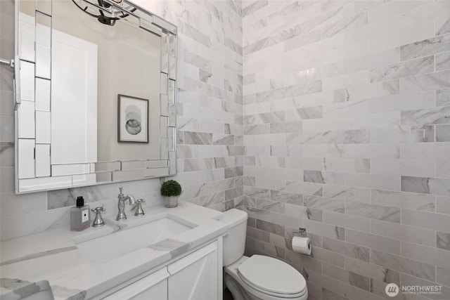 bathroom with vanity, toilet, and tile walls