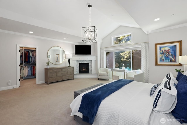 bedroom featuring a walk in closet, a chandelier, carpet, baseboards, and a lit fireplace