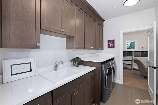 laundry room with a sink, cabinet space, light tile patterned flooring, and washer and dryer