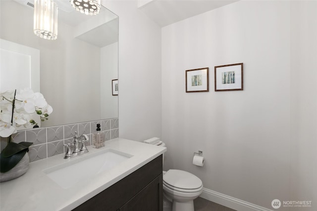 bathroom with vanity, tasteful backsplash, baseboards, and toilet
