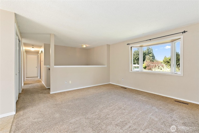 empty room with carpet flooring, a textured ceiling, and baseboards