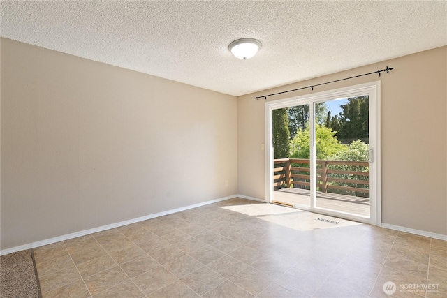 empty room with a textured ceiling and baseboards