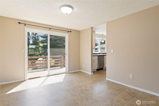 spare room featuring a textured ceiling, a sink, baseboards, and light tile patterned floors