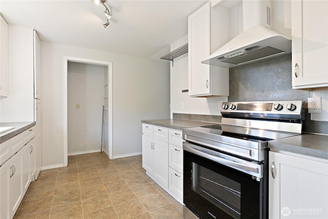 kitchen with electric range, under cabinet range hood, white cabinetry, dark countertops, and baseboards