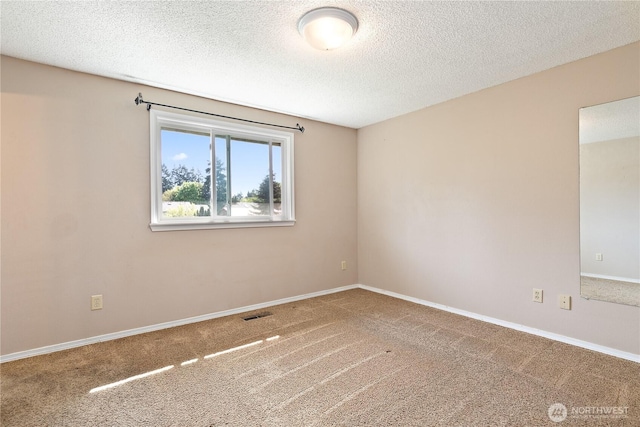 empty room featuring carpet, a textured ceiling, and baseboards