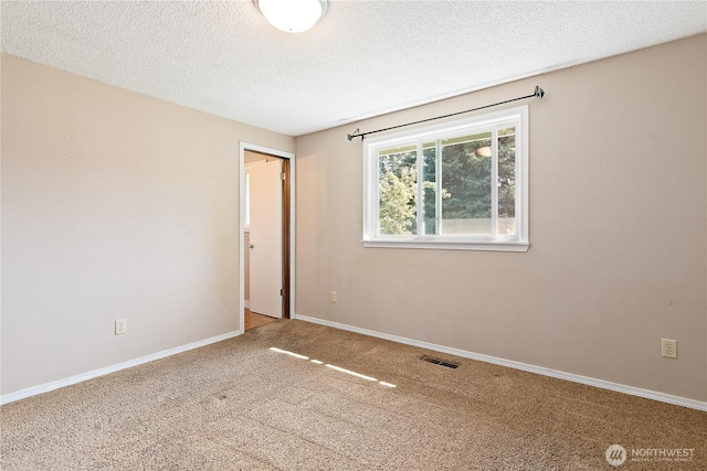 carpeted empty room featuring a textured ceiling and baseboards