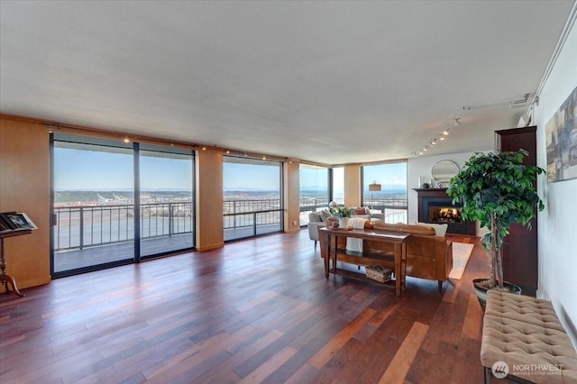 1 N Stadium Way Unit 16, Tacoma, WA 98403 - living room with rail lighting, a water view, a warm lit fireplace, wood finished floors, and expansive windows