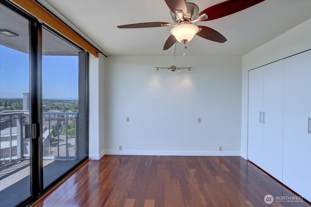 1 N Stadium Way Unit 16, Tacoma, WA 98403 - unfurnished bedroom featuring dark wood-style floors, baseboards, a ceiling fan, a wall of windows, and a closet