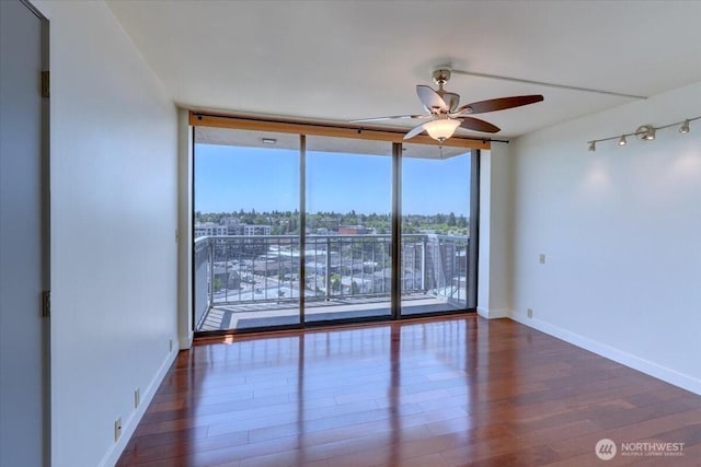1 N Stadium Way Unit 16, Tacoma, WA 98403 - empty room featuring floor to ceiling windows, ceiling fan, wood finished floors, and baseboards