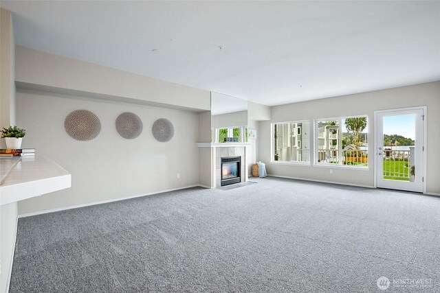 unfurnished living room featuring a fireplace, baseboards, and carpet