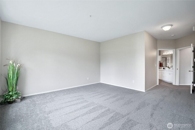 spare room with dark carpet and baseboards