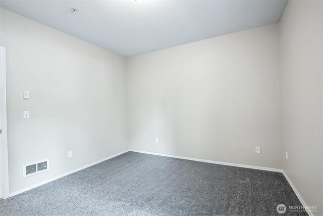 unfurnished room featuring baseboards, dark colored carpet, and visible vents