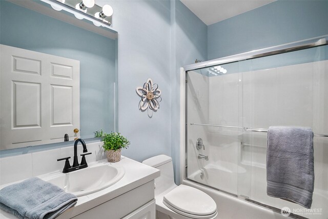 full bathroom featuring vanity, combined bath / shower with glass door, and toilet
