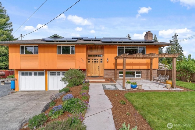 view of front facade with driveway, solar panels, a garage, and a pergola