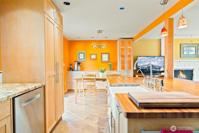 kitchen featuring butcher block counters, dishwasher, pendant lighting, light tile patterned flooring, and a fireplace