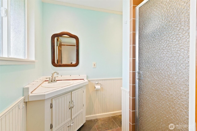 full bathroom featuring a wainscoted wall, a stall shower, and vanity