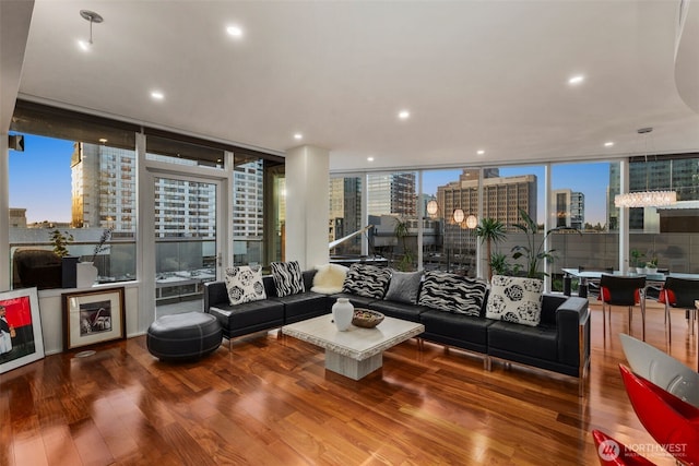 living room with plenty of natural light, a view of city, wood finished floors, and floor to ceiling windows
