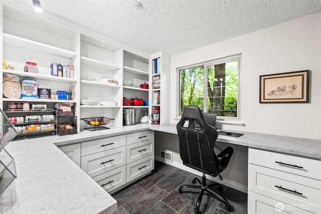office area with built in desk and a textured ceiling