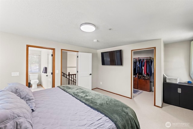 bedroom with a walk in closet, carpet floors, a closet, ensuite bath, and baseboards