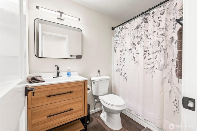 bathroom with toilet, vanity, and wood finished floors